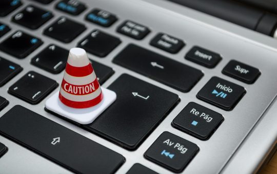 Miniature caution cone on a computer keyboard symbolizing data security and control.